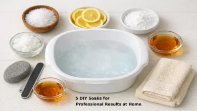 Five DIY foot soak ingredients from Dollar Tree including Epsom salt essential oil lemon baking soda and coconut oil arranged beside a white foot basin on a clean bathroom floor