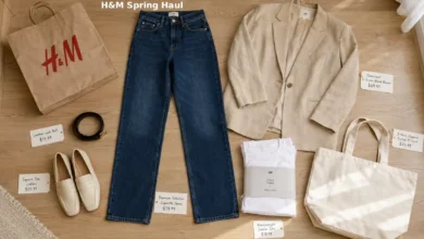 H&M Spring 2026 haul spread on a white background including the Premium Selection cigarette jeans in medium indigo wash, an oversized beige linen-blend blazer, a pack of organic cotton white t-shirts, a black leather-look belt, cream square-toe loafers, and a canvas tote bag. The $40 jeans are highlighted with a small price tag.