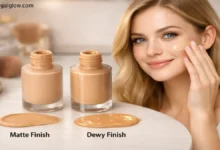 A fair-skinned woman applies liquid foundation to her cheek beside two open bottles labeled “Matte Finish” and “Dewy Finish” on a white vanity.
