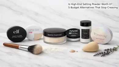 Five budget setting powder compacts and loose powders lined up on a marble surface including e.l.f., Maybelline, NYX, RCMA, and The Creme Shop, next to a luxury Laura Mercier Translucent Loose Setting Powder jar – affordable drugstore alternatives that prevent creasing.