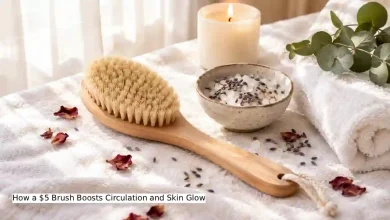 Natural bristle dry body brush on a white towel next to a small bowl of sea salt and dried lavender, with soft morning light – affordable DIY body brushing tool for circulation and glowing skin under $5.