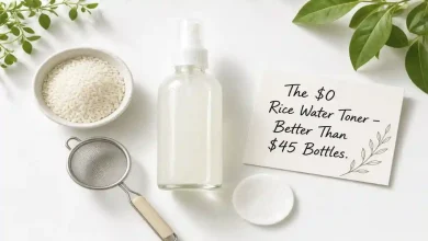 A glass spray bottle filled with homemade rice water toner next to a bowl of rice, a strainer, and a cotton pad. A sign says "$0 vs $45 โ Same Glow."
