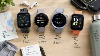 Four budget fitness trackers with built-in GPS under $100 lined up on a wooden surface, including Amazfit Bip 6, Amazfit Active 2, CMF Watch Pro 2, and Amazfit Bip 5 – standalone GPS smartwatches for running and hiking without a phone.